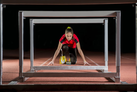 Athlete on the starting blocks with hurdles