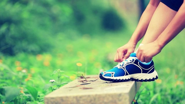 woman runner tying shoelace in the nature