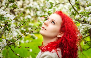 the girl with red hair in the blossoming garden