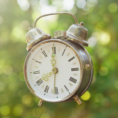 old clock alarm with natural green bokeh background