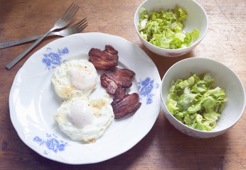 Breakfast for two consisting of eggs, bacon and salad