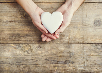 Hands of man and woman holding a heart together.