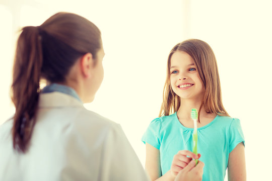 female doctor giving toothbrush to smiling girl