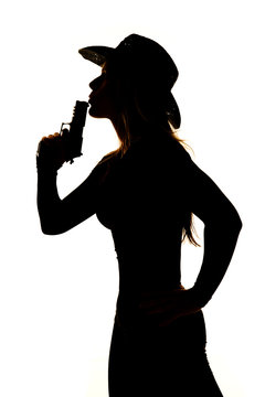 silhouette of woman cowboy hat with gun blow close