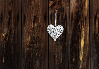 White wicker heart on wooden background