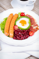 Egg fried in a green pepper, sausages, bacon and red beans