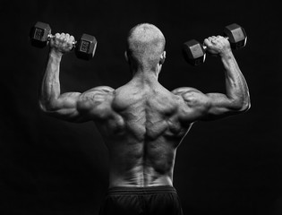 Fototapeta premium Back of muscular male bodybuilder with dumbbell