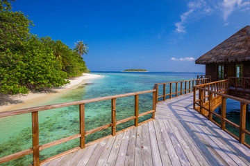 Bridge leading to overwater bungalow in blue lagoon - Powered by Adobe