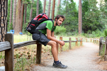 Hiking man resting with backpack in forest park