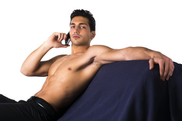 Shirtless young man talking on cell phone sitting on couch