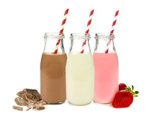 Différentes saveurs de lait dans des bouteilles isolées sur blanc