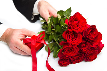 man's hand with red roses bouquet and gift box