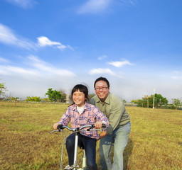 happy Father teaching his daughter to ride bicycle