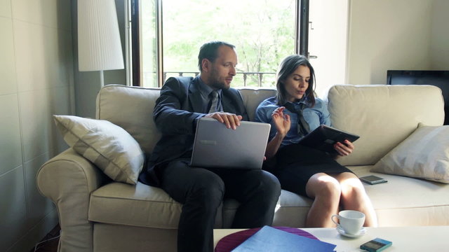 Business couple with tablet computer and laptop having break