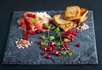 Sliced prosciutto with herbs and pomegranate seeds