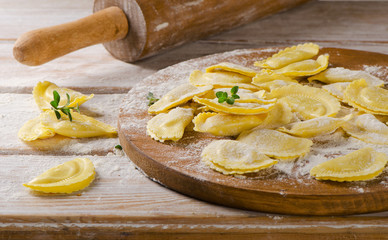 Fresh Ravioli on with flour  on a  wooden backround.