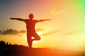 Fototapeta na wymiar Silhouette of young man doing yoga at sunset