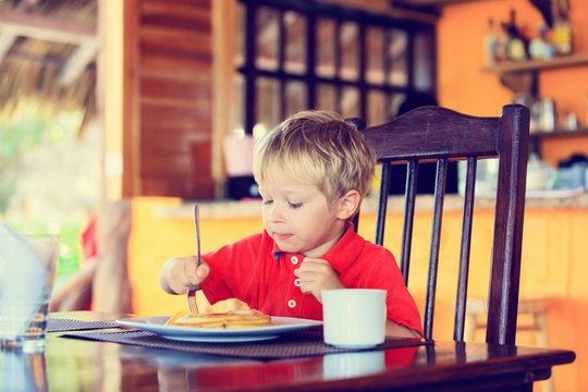 Little Boy Eating Pancakes In Cafe