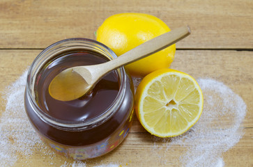 Jar of dark honey a wooden spoon and lemons
