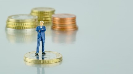 A successful miniature businessman standing on money