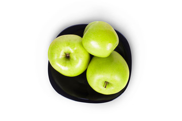 Three green apples on a black plate