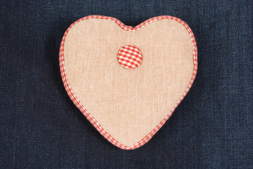 Fabric handmade heart on a blue denim jeans background