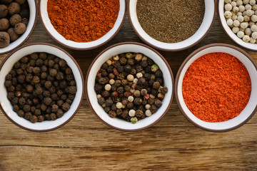 Various peppers in ceramic dishes on the wooden table