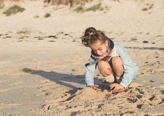 Little girl playing in the sand of the beach