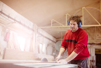 Carpenter sawing wooden planks