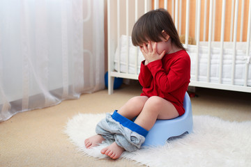 crying toddler sitting on potty at home - obrazy, fototapety, plakaty