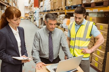 Focused warehouse team working together on laptop