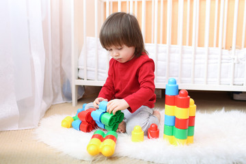 nice toddler boy playing plastic blocks