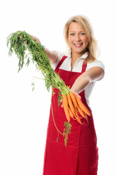Hausfrau mit Schürze zeigt einen Bund Karotten