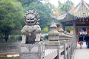 Naklejka premium stone lion sculpture on the fence in the park