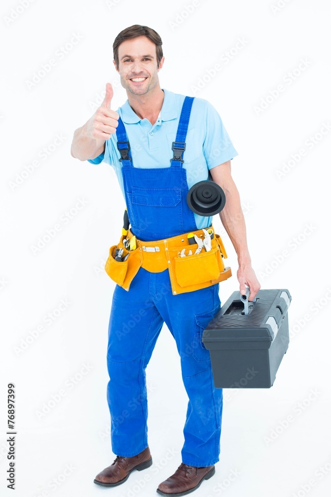 Poster plumber carrying tool box while gesturing thumbs up