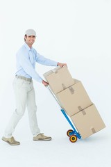 Happy delivery man pushing trolley of cardboard boxes