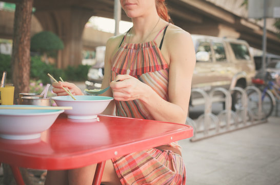 Woman eating noodles in the street