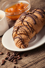 Breakfast with coffee, jam, cookies and croissants on table