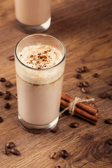 Full glass of milk cocktail and coffee beans on the wooden backg