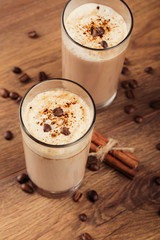 Full glass of milk cocktail and coffee beans on the wooden backg