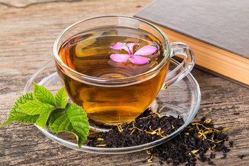 Glass Cup Tea with pink flower and Mint Leaf, on brown wooden pa