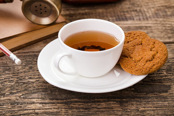 ivory tea cup with sweet cookie, old telephone and book on woode