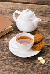 Image of ivory tea cup with sweet cookie, kettle and money on wo
