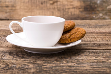 Ivory tea cup with sweet cookie on wooden palette
