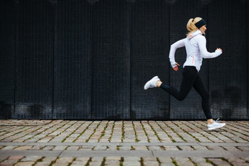 Young woman running on sidewalk in morning