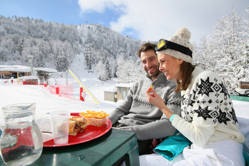 Couple of skiers having a snack on skiing day