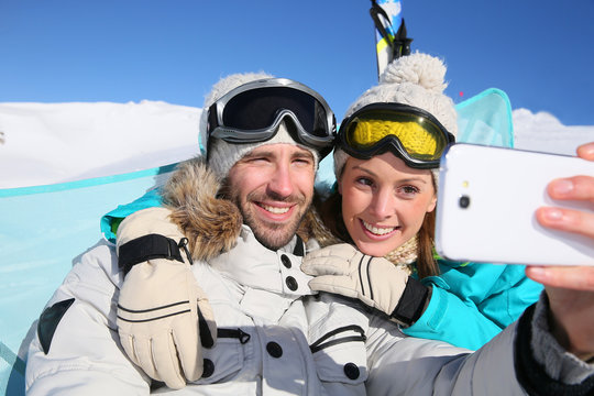 Couple of skiers making selfy with smartphone