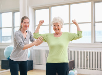 Fit senior woman showing her biceps at gym - Powered by Adobe