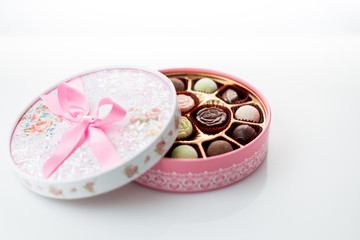 Chocolates in pink box on white background
