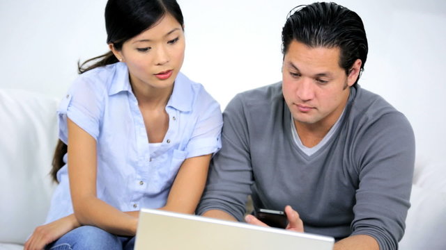 Ethnic Couple Using Wireless Laptop Trying Solve Financial Problems 